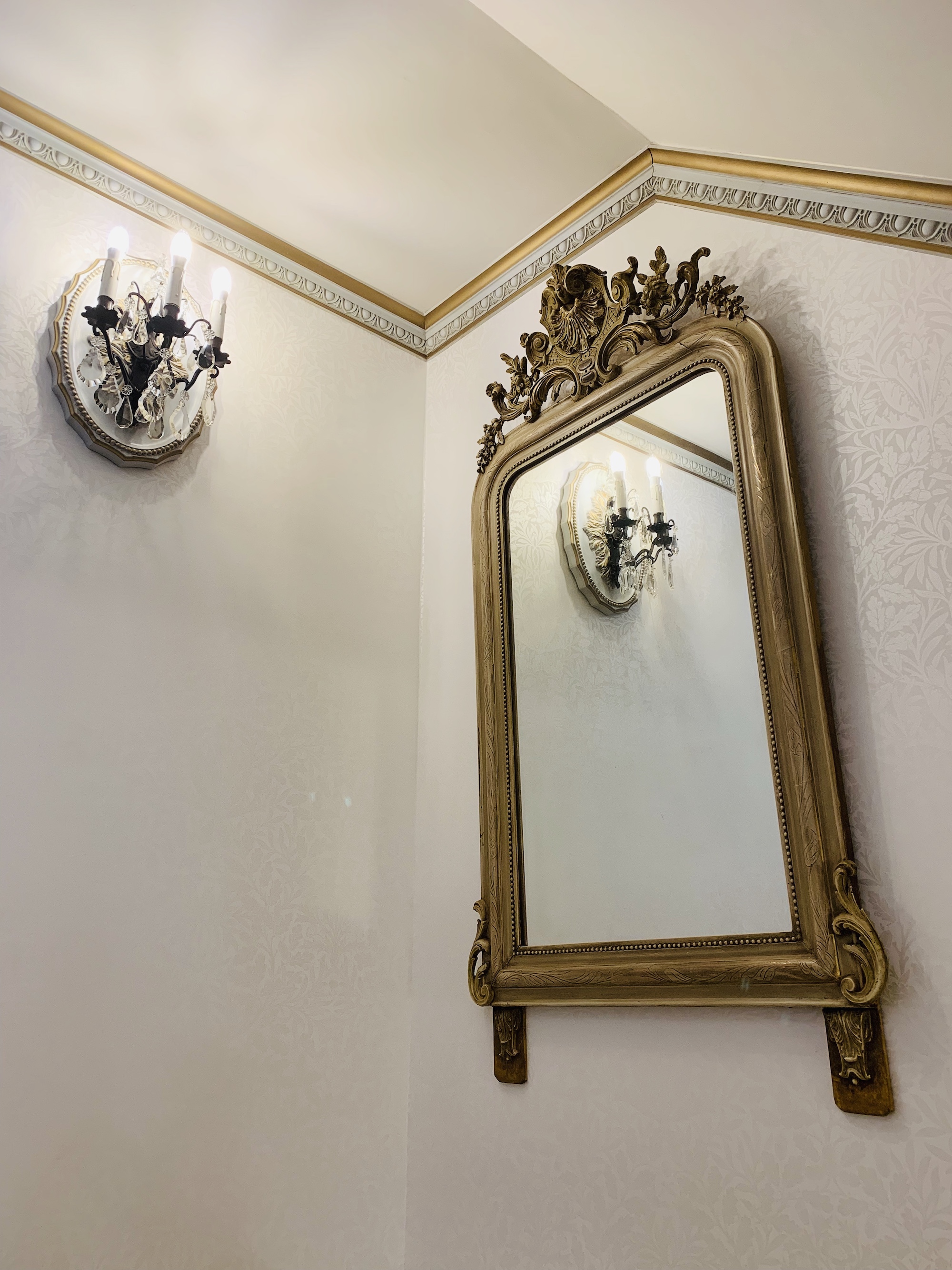 Antiker französischer Spiegel und Wandleuchten in dem stilvollen Treppenhaus
